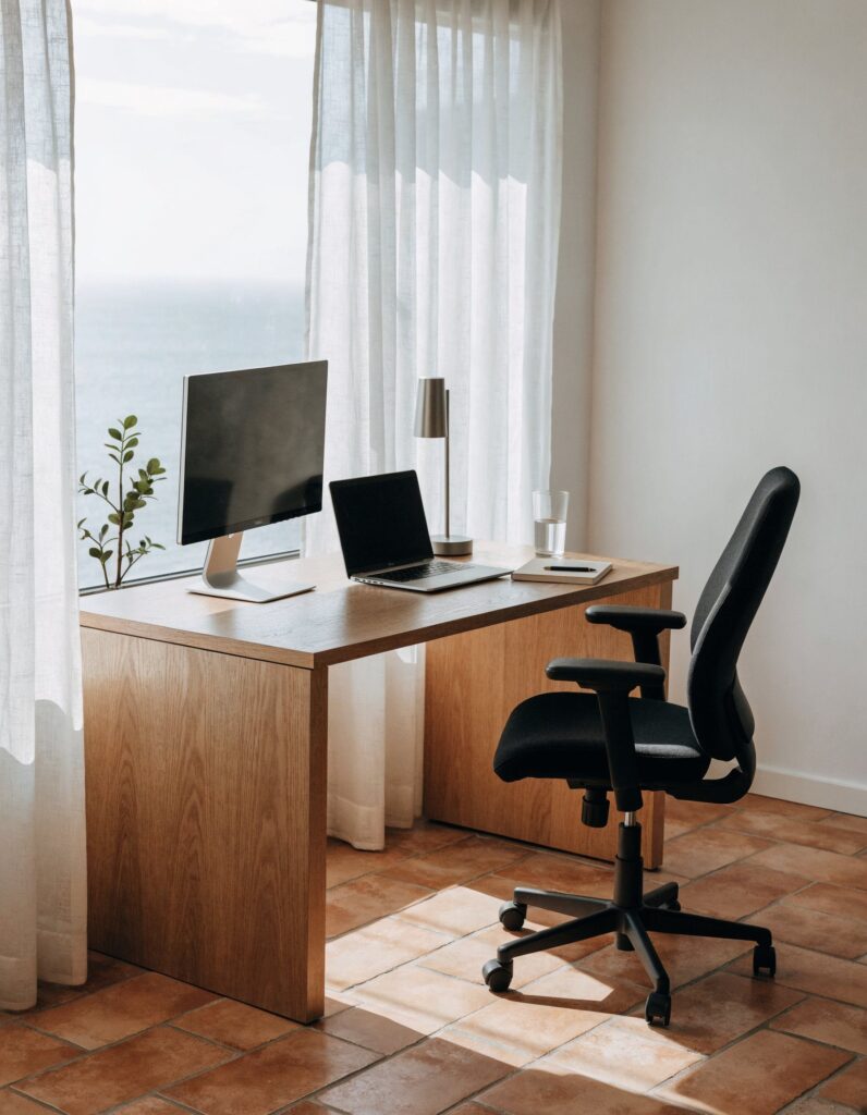 Escritorio junto a la ventana con portátil, aro de luz y silla ergonómica blanca