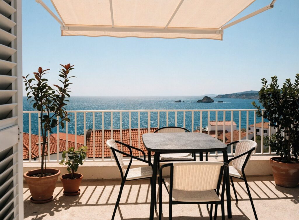 Terraza exterior con mesa, sillas, toldo y plantas, con vistas al mar